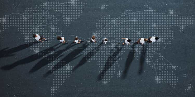 School children in uniforms walking in row across world map